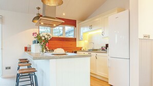 A modern kitchen with a central island, white cabinetry, and a built-in refrigerator.