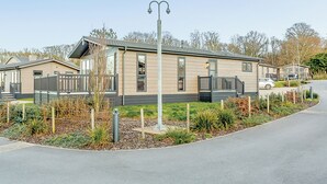 A modern mobile home with a flat roof, large windows, and a fenced garden area.