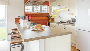 A modern kitchen with white cabinetry, a central island, and a gas stove. - Fresh and contemporary styled lodge. (Axminster)