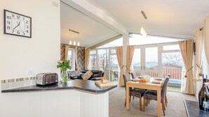 Eine moderne Küche mit eingebautem Toaster, ein Essbereich mit Holztisch und Stühlen sowie ein großes Fenster mit Vorhängen.