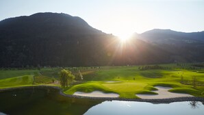 A golf course with a pond and mountains in the background. - Hotel Jägerhof (Mayrhofen)