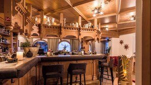 A bar area with wooden decor, bar stools, and a large potted plant. - Hotel Jägerhof (Mayrhofen)