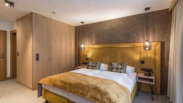 A modern hotel room with a large bed, wooden panel walls, and a small bedside table.
