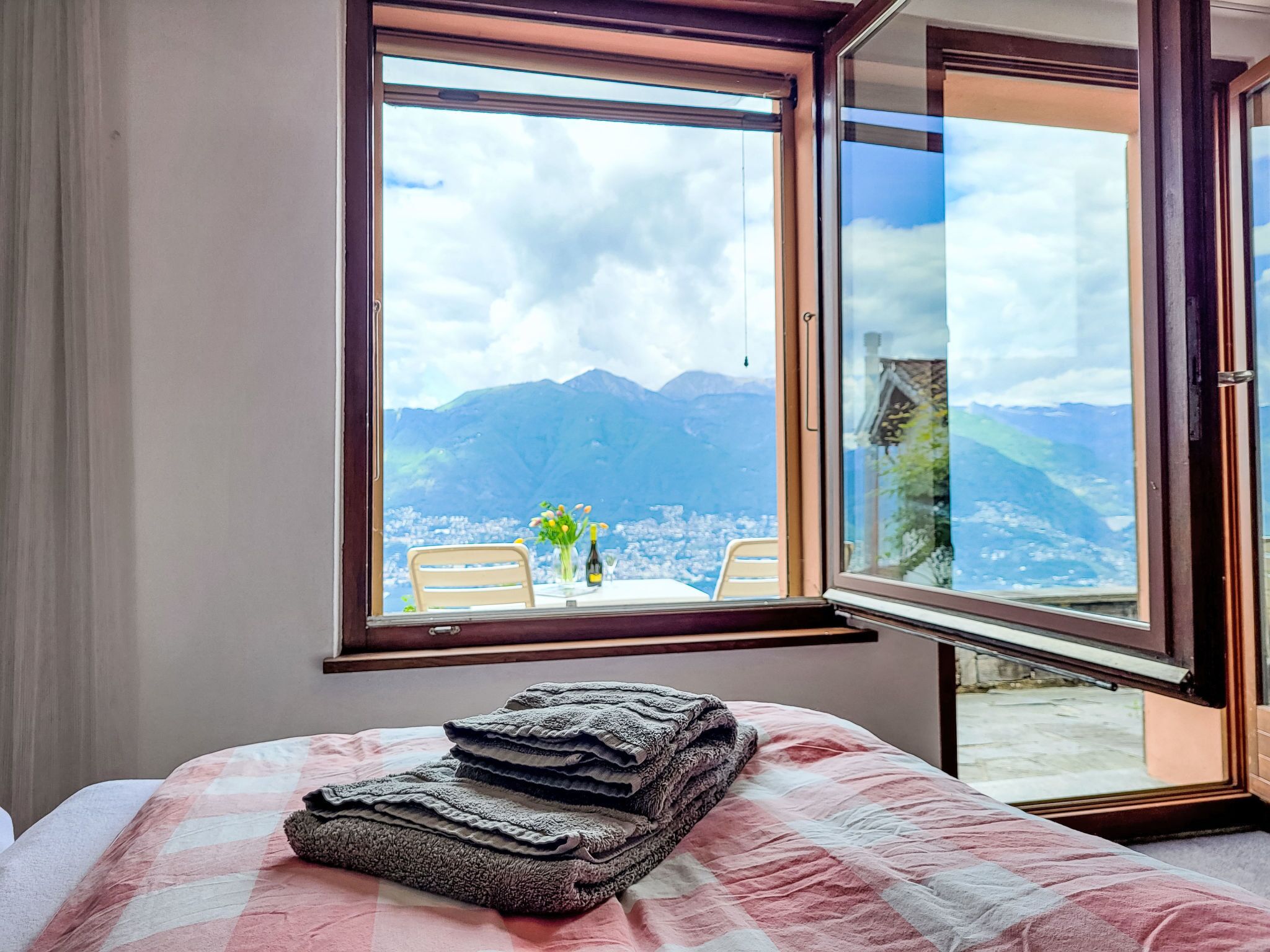 A bedroom with a large window overlooking a mountainous landscape.