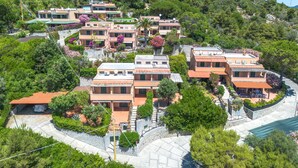 A hillside residential area with terraced houses, featuring balconies, gardens, and a mix of architectural styles. - Sunny House by Interhome (Marina di Campo)