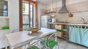 A modern kitchen with a white countertop, stainless steel appliances, and a green chair. - Sunny House by Interhome (Marina di Campo)
