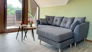 Ein modernes Wohnzimmer mit einem grauen Ecksofa, einem kleinen runden Tisch und einem Sessel.