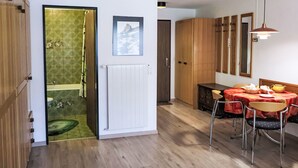 A modern kitchen with wooden cabinets, a dining table with chairs, and a hanging light fixture. - Pasadena by Interhome (Zermatt)