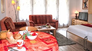 A cozy hotel room with a bed, two armchairs, a dining table with breakfast, and a TV on a wooden cabinet. - Pasadena by Interhome (Zermatt)