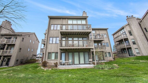 Un immeuble résidentiel à plusieurs étages, doté de balcons, d’un porche avant couvert et d’une pelouse verdoyante.