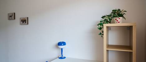 A room with a desk, chair, and a shelf with a plant.