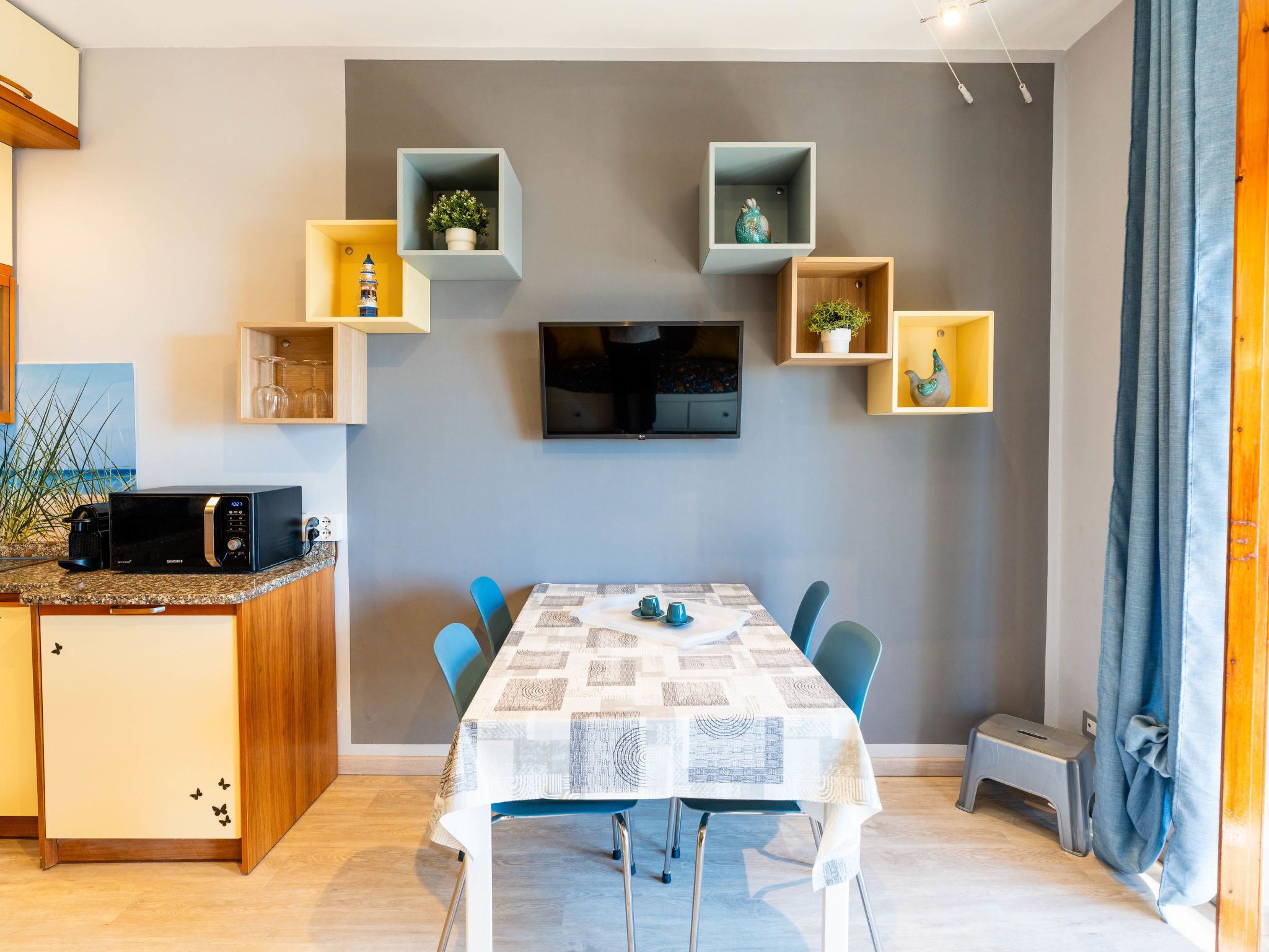 A modern kitchen with a microwave, a dining table with chairs, and built-in shelves with decorative items.
