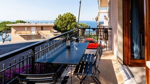 A balcony with a table and chairs, a red car parked outside, and a view of the sea and buildings in the background. - casa Peggy by Interhome (Santo Stefano al Mare)