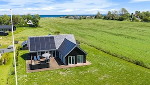 A modern house with a solar panel roof, a large patio with outdoor furniture, and a view of the sea. - "Ung" - 460m from the sea by Interhome (Otterup)