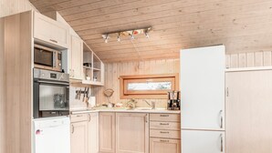 A modern kitchen with wooden cabinets, a built-in oven, microwave, and refrigerator.