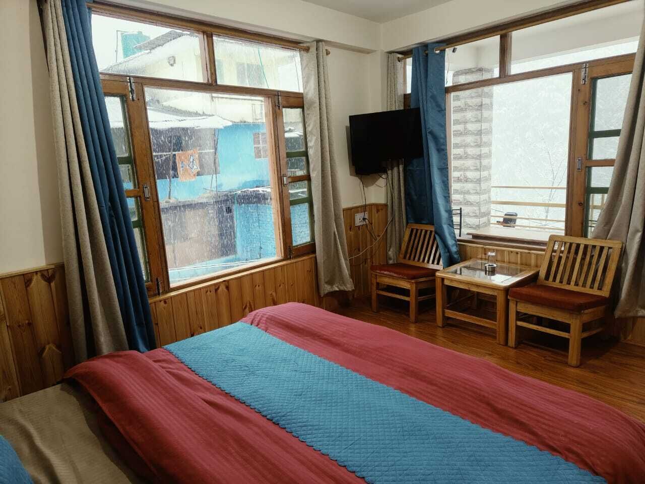 A room with a bed, a TV, a table, and two chairs.