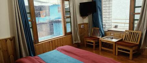 A room with a bed, a TV, a table, and two chairs.
