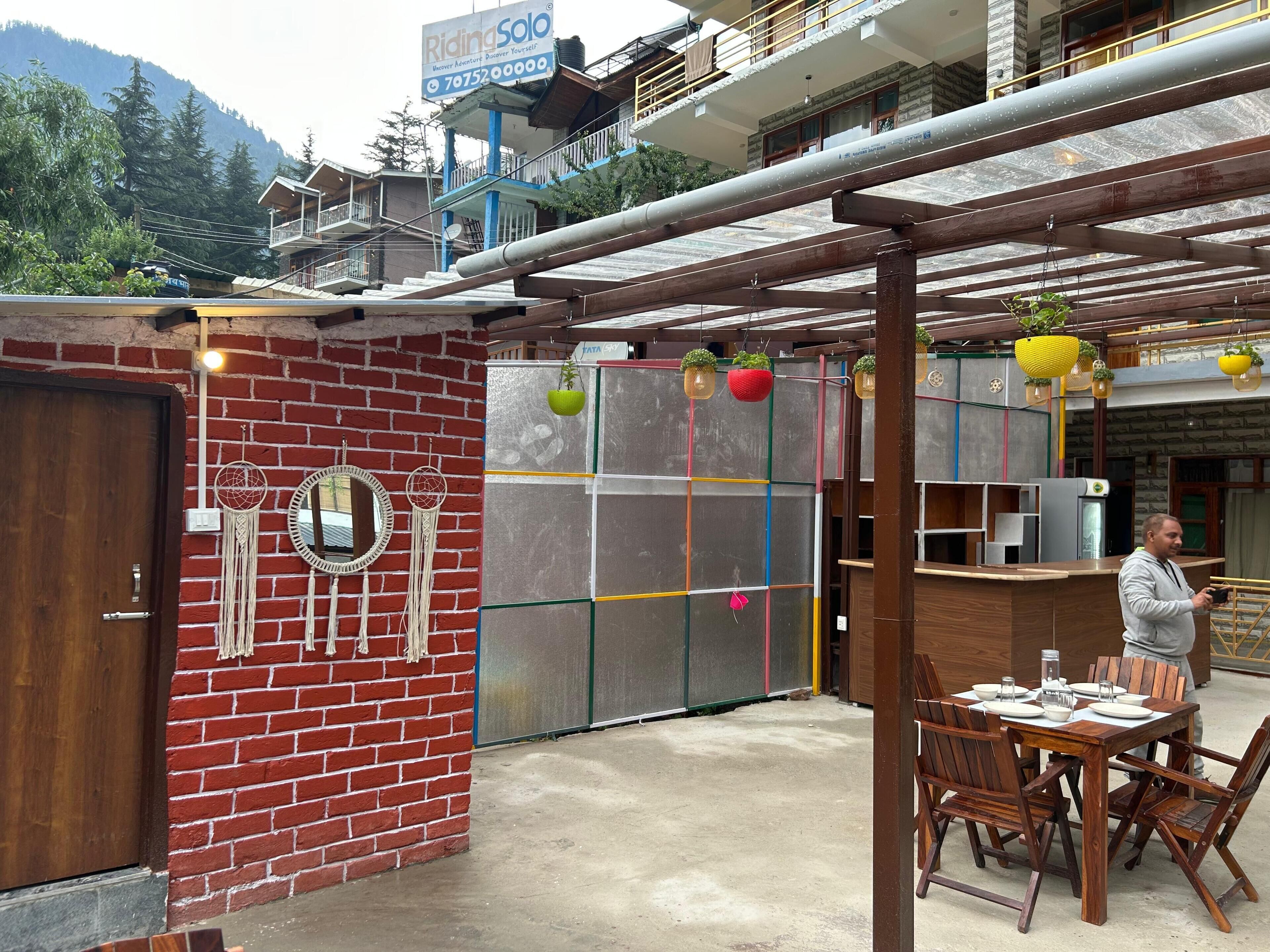 A restaurant with a brick wall, a wooden table with chairs, and a view of the mountains.