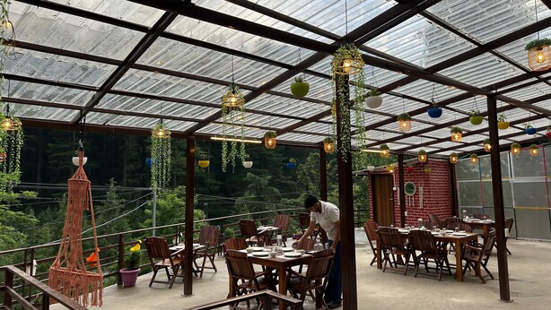 Un restaurant dot é d’un plafond en verre, de tables en bois et de plantes suspendues.
