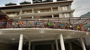 Un immeuble à plusieurs étages doté de balcons et d’un espace couvert agrémenté de plantes en pot.