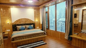 Une chambre dans une cabane en bois, avec un lit, des tables de chevet, une fenêtre avec des rideaux et un plafond en bois.