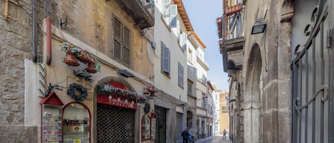Una calle estrecha con edificios que tienen puertas abovedadas y balcones.