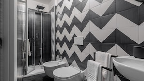 A modern bathroom with a shower, bidet, and sink, featuring a geometric tile pattern on the walls. - Basco Guest House (Viterbo)
