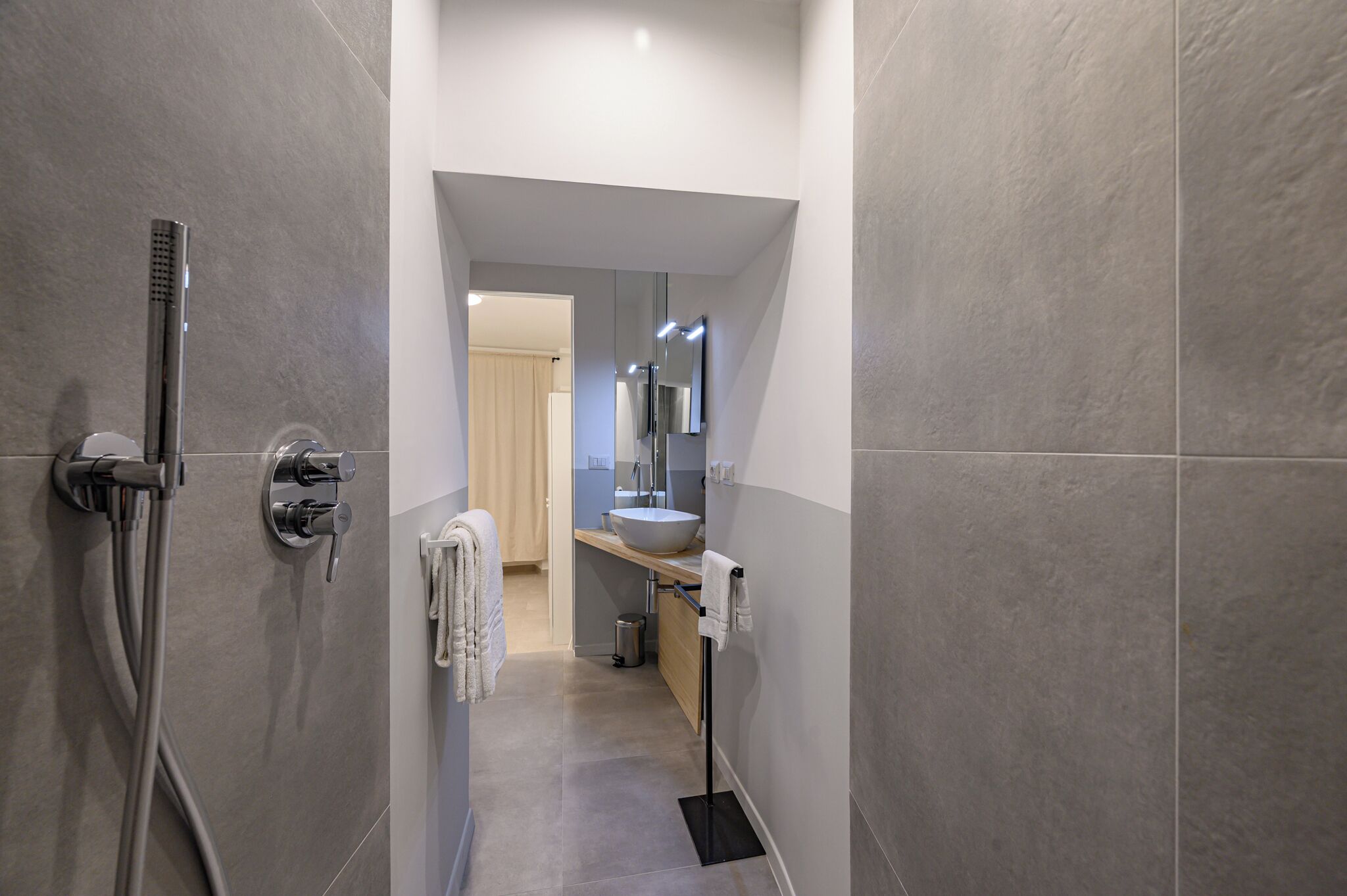 Un baño moderno con ducha, lavamanos y espejo.