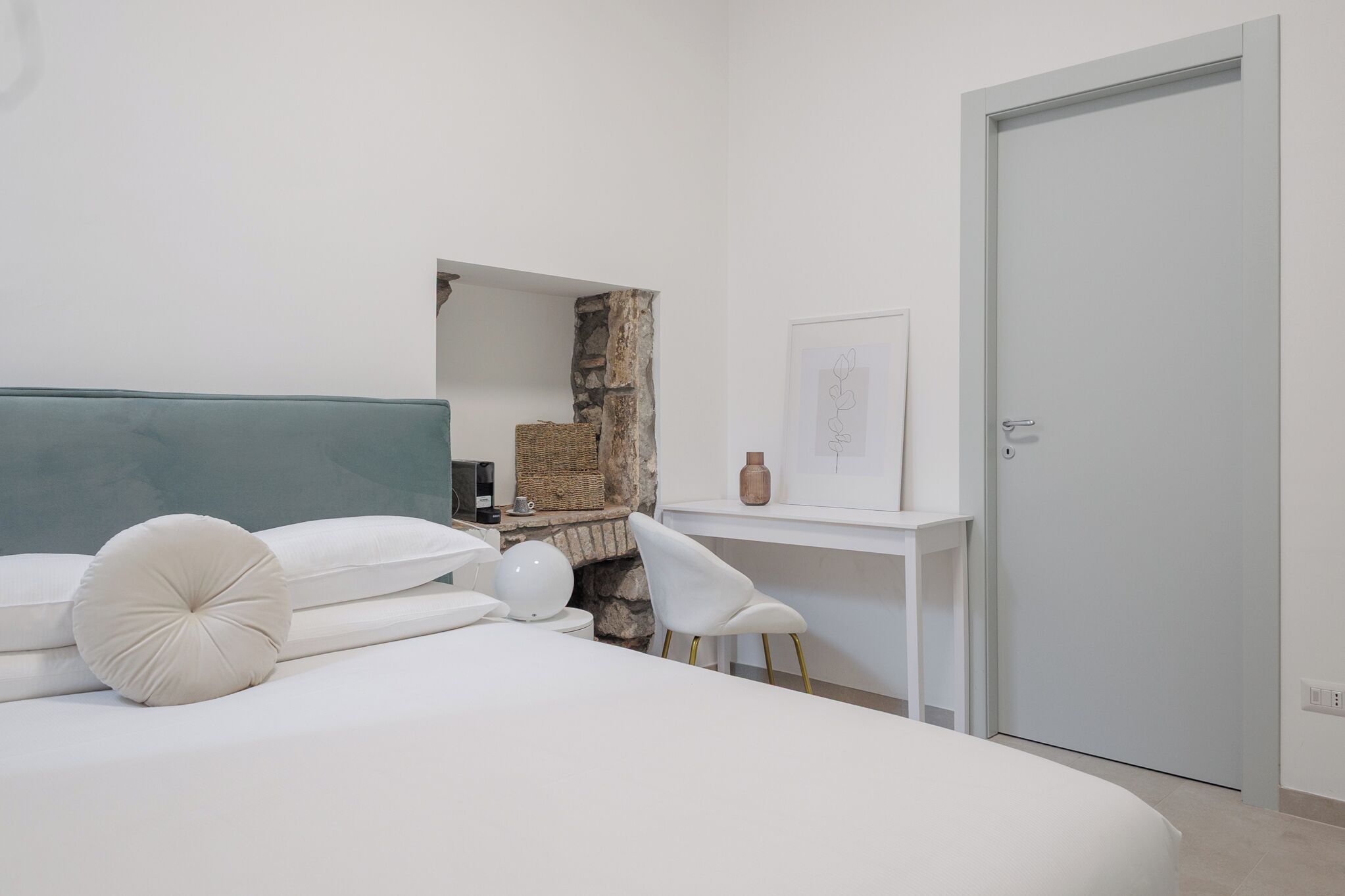 A modern bedroom with a bed, a desk, and a door.