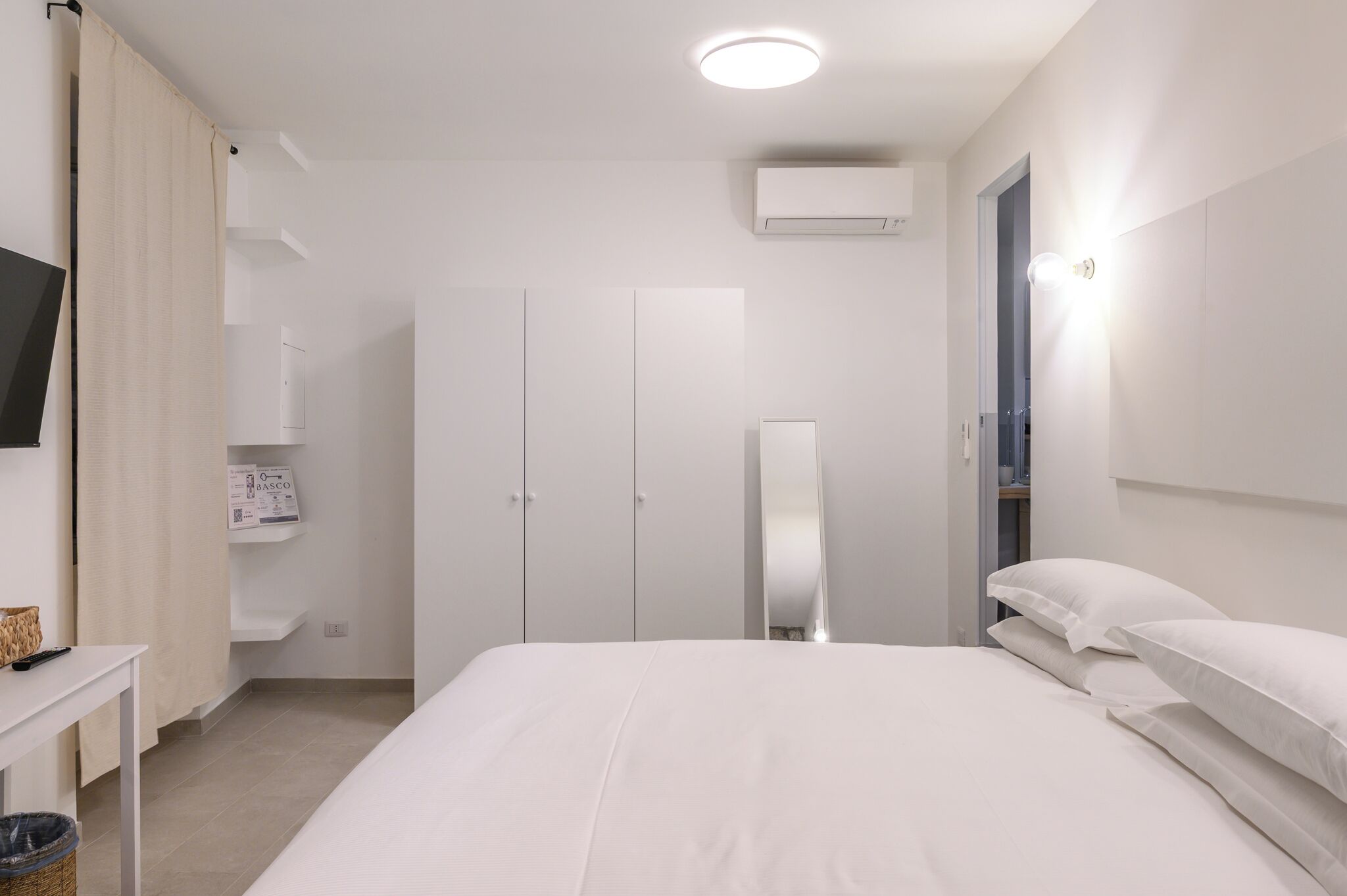 Een moderne hotelkamer met een groot bed, een flatscreen televisie, een kledingkast en een spiegel.