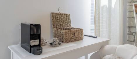 Un bureau blanc avec une machine à café Krups, un panier en osier et un petit objet décoratif.