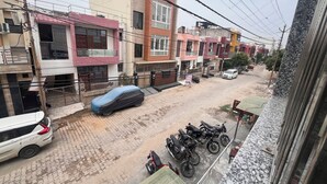 Un carrer residencial amb edificis d'alguns pisos, cotxes i motos estacionades.