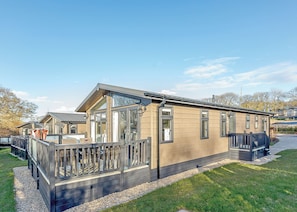 En moderne vogn med terrasse, store vinduer og grusvej.