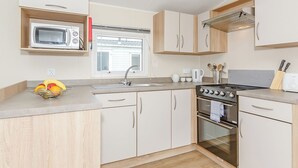 Eine kleine Küche mit Mikrowelle, Herd, Spüle und Holzschränken.