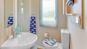 Ein Badezimmer mit Waschbecken, Toilette und Fenster mit Jalousien.
