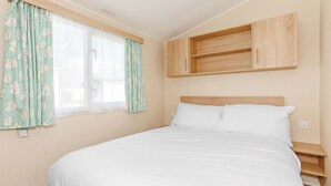 Ein Schlafzimmer mit einem Bett, einem Fenster mit Vorhängen und eingebauten Holzbögen über dem Bett.