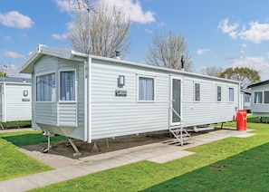 A white mobile home with a sliding door, windows, and a small porch area.