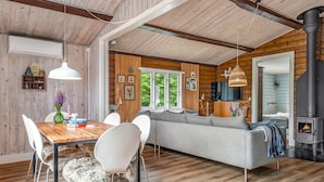 Un intérieur de chalet chaleureux avec un coin repas, un canapé et un poêle à bois.