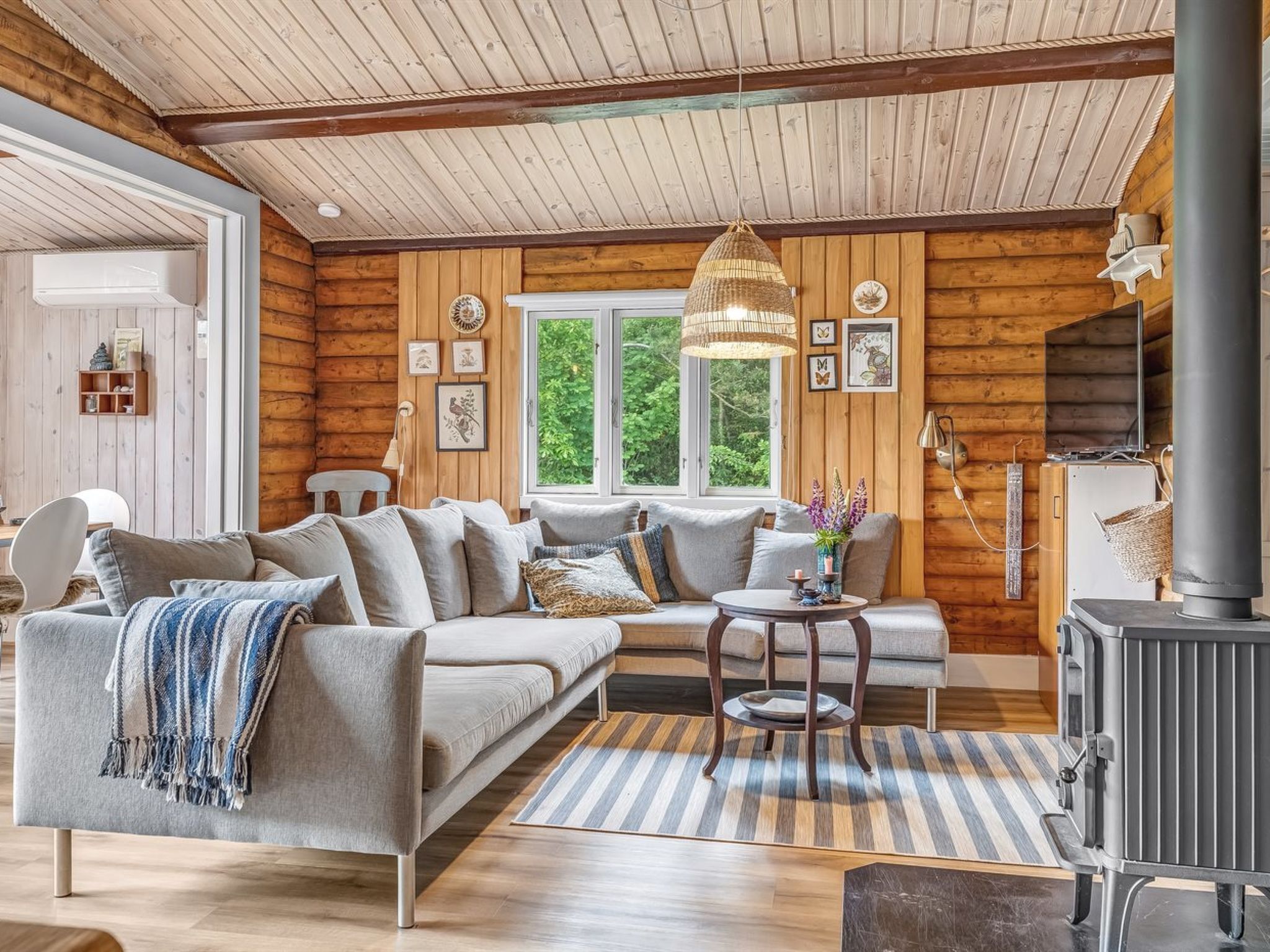 L’intérieur d’un chalet confortable, avec une grande banquette, une petite table ronde et un poêle à bois.