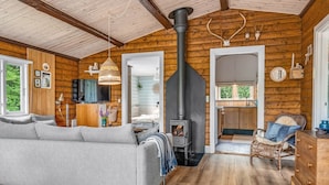 Un intérieur de chalet chaleureux avec un canapé, un coin repas, une cuisine et une cheminée.