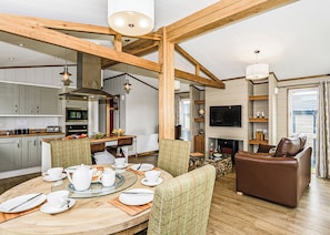 A spacious living area with a dining table set for four, a fireplace, a television mounted on the wall, and a cozy seating area with a brown leather sofa. - 1 bedroom accommodation in Greystoke, Nr Ullswater (Greystoke, Nr Ullswater)