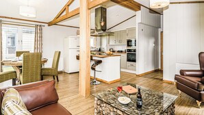 A modern kitchen with wooden beams, a dining area with a table and chairs, and a living room with a sofa and a coffee table. - 1 bedroom accommodation in Greystoke, Nr Ullswater (Greystoke, Nr Ullswater)