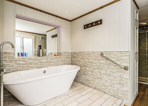 Ein Badezimmer mit einer freistehenden Badewanne, einem Spiegel, einem Handtuchhalter und einer Duschkabine.