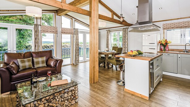 A spacious living area with a wooden ceiling, a glass coffee table, a leather sofa, and a kitchen with white cabinets and a stainless steel range hood. - 1 bedroom accommodation in Greystoke, Nr Ullswater (Greystoke, Nr Ullswater)