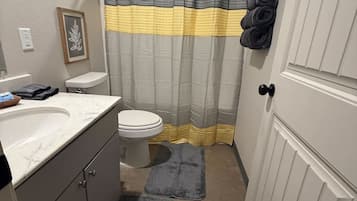 Un baño pequeño con inodoro, lavamanos y cortina de ducha.