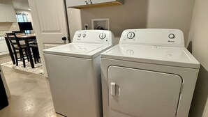 A laundry room with two white front-loading washers and a cabinet above them. - Calming Comfort Stay (Clovis)