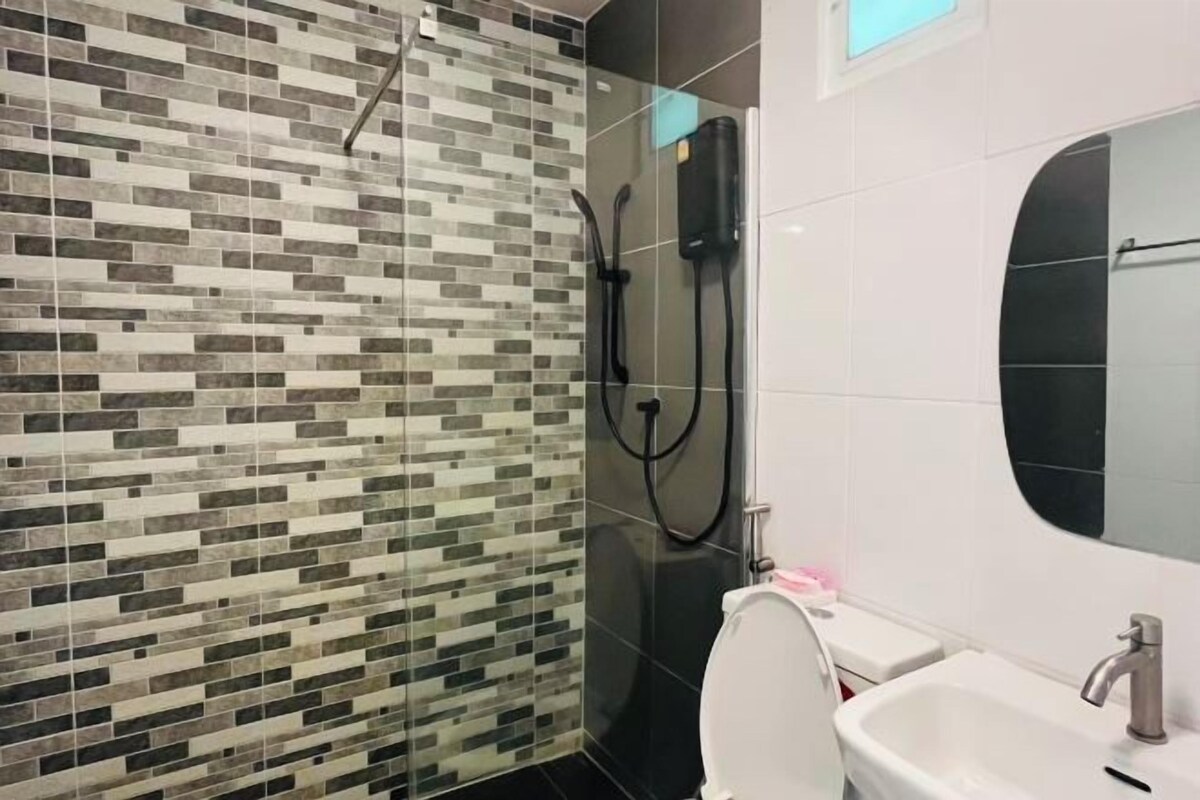 A modern bathroom with a mosaic tile shower wall, a toilet, and a sink with a mirror.