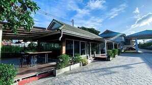 Een restaurant met terras, overdekte ruimtes en een geplaveid pad.