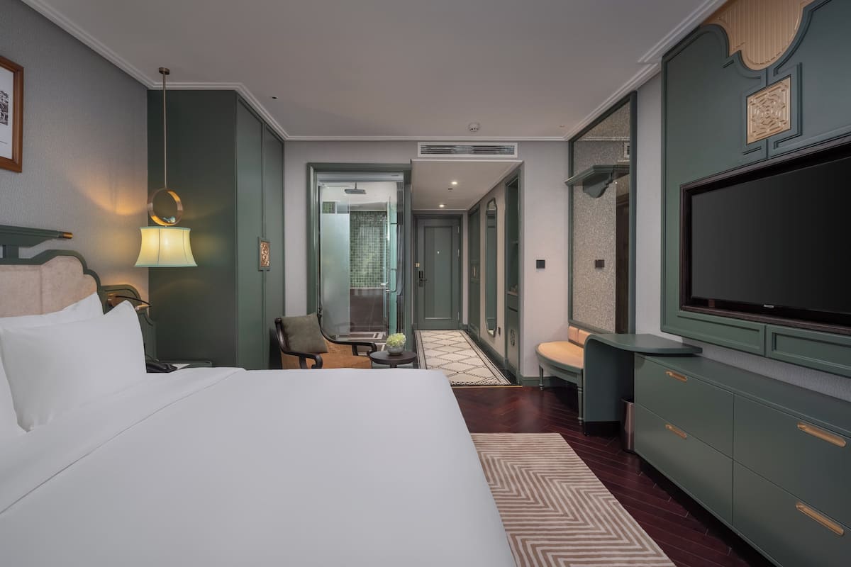 Hotellihuone, jossa on suuri sänky, televisio, työpöytä ja tuoli.