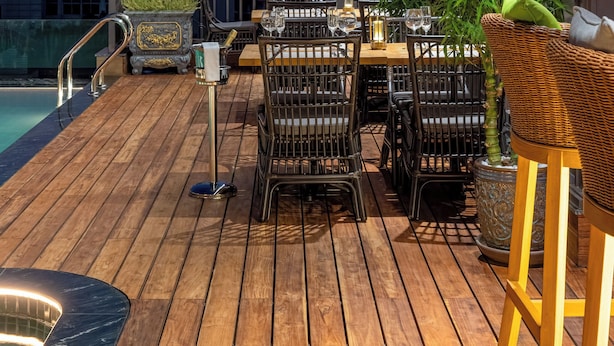 Un bar situé sur le toit, avec un plancher en bois, des tables et des chaises, et une piscine.